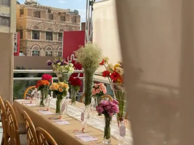 طاولة الورشة نفسها مع مبنى صنعاني قديم في الخلفية