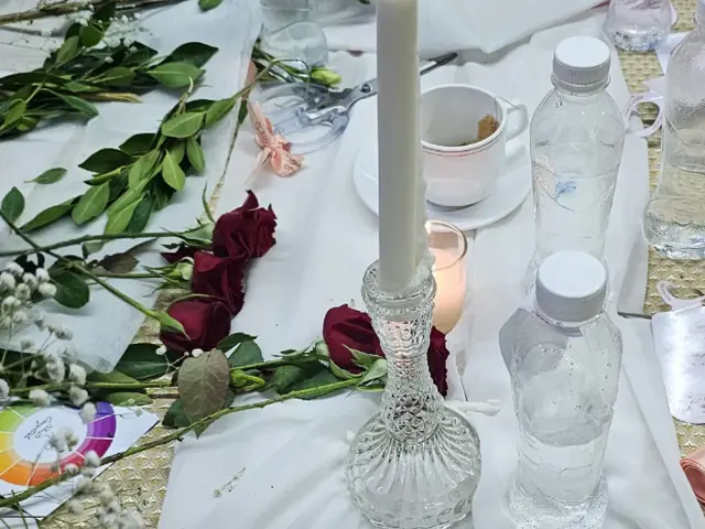 من ورشة تنسيق الزهور: جوري أحمر وشمعة وعجلة الألوان وأدوات التنسيق