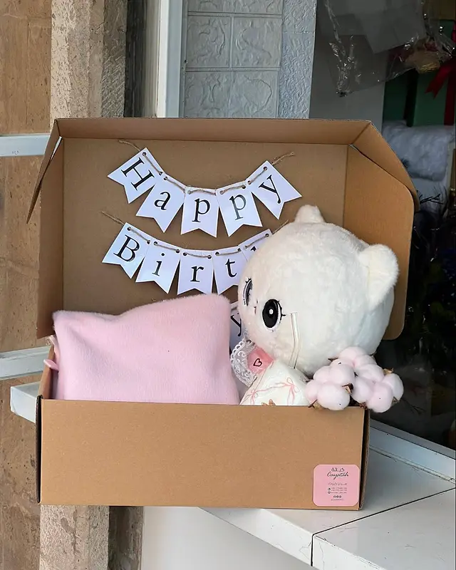 صندوق هدية عيد ميلاد من كياتة في صنعاء — لافتة Happy Birthday ودبدوب أبيض وبطانية وردية داخل صندوق كرافت
